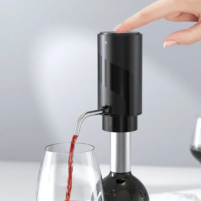 The AeroVinum on top of a wine bottle, a fingertip pressing its cap and red wine running from the steel spout into a glass