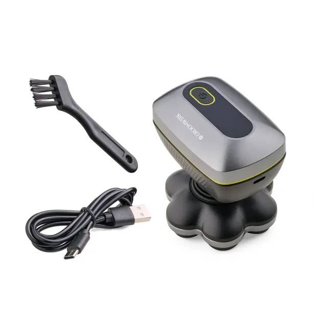 The GroomWerk shaver standing upright on its head unit, with a black cleaning brush and a coiled black USB cable beside it, on white