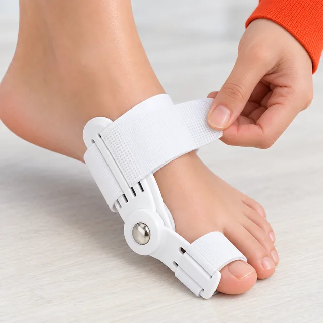 A hand pulling the wide strap of the white HalluxGuard snug around a bare forefoot, the silver pivot at the big toe joint