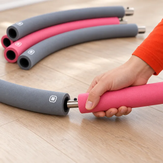 A hand pushing the pin end of a pink HoopaLoop section into the open end of a gray one, more sections lying behind