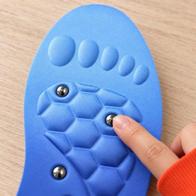 A fingertip on a polished metal stud in the blue honeycomb forefoot of an IonStride insole, the toe pads above it