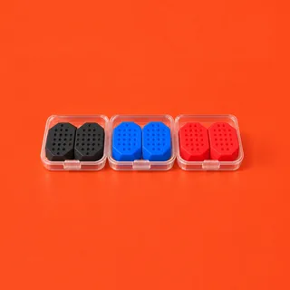 The JawCore kit on a vermilion background: three pairs of dimpled silicone trainers, black, blue and red, each pair in a clear case