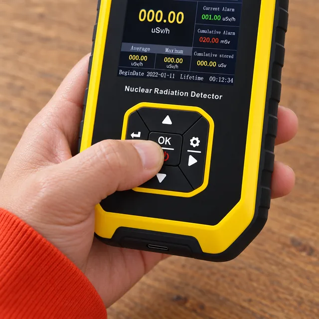 Un pulgar pulsa la tecla OK del teclado enmarcado en amarillo del PrecisionRad, con su pantalla encendida encima