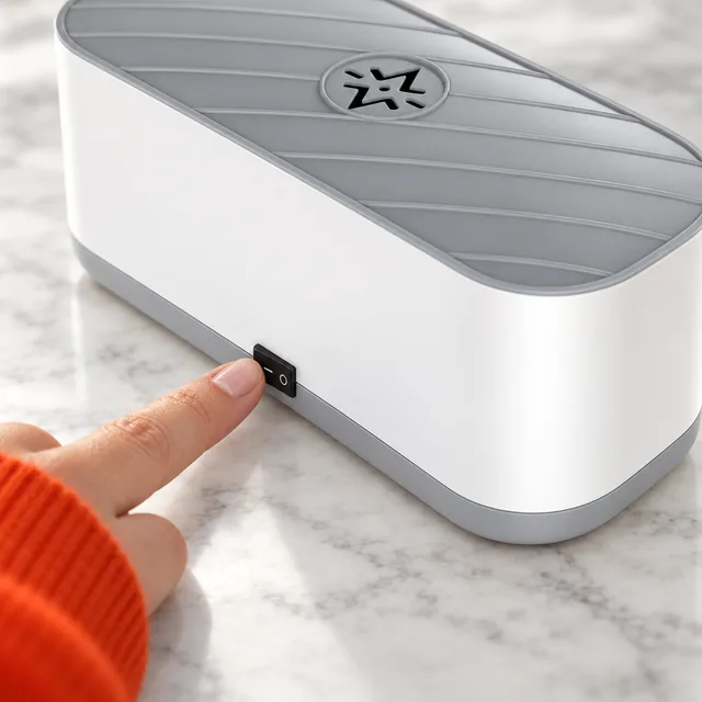 A fingertip on the small black switch low on the side of the closed white Purityx