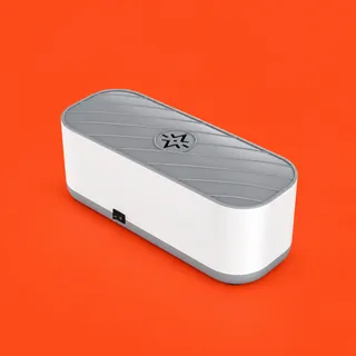 Purityx, the white oblong glasses cleaner with its gray ribbed lid and a black switch low on one side, on a vermilion background