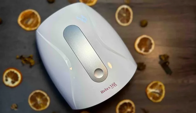 The white RelaxMit seen from above on a dark wooden table among dried orange slices, its touch strip unlit