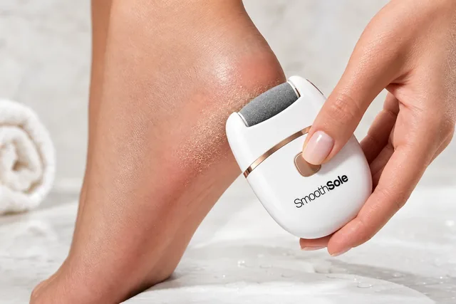 A hand holding the white SmoothSole against a bare heel, fine skin dust on the heel beside the roller