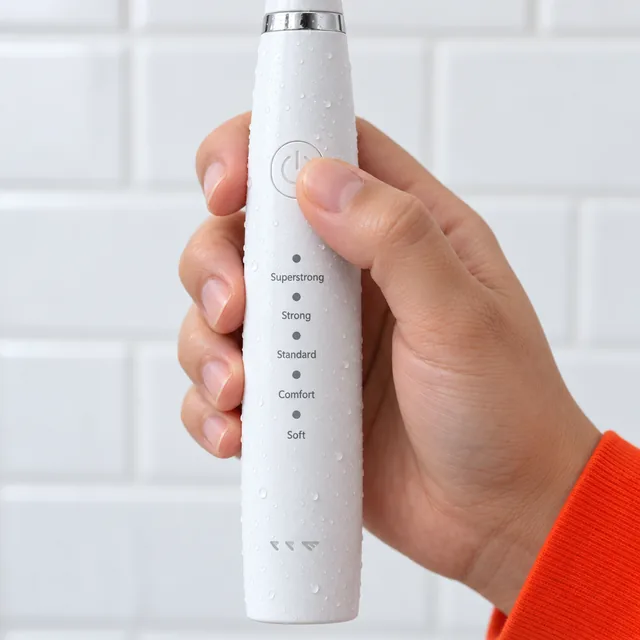 Un pouce sur le bouton rond de mise en marche de la SonicScale blanche, les noms des cinq niveaux, de Superstrong à Soft, imprimés en dessous