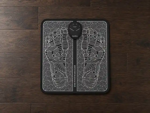 The black Sontho mat with its white line art of two foot soles, the oval controller at the top of its center band, lying on a dark wooden floor