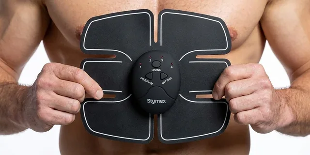 Zwei Hände halten das schwarze Stymex-Pad mit sechs Segmenten und der ovalen Steuereinheit an einen nackten Oberkörper