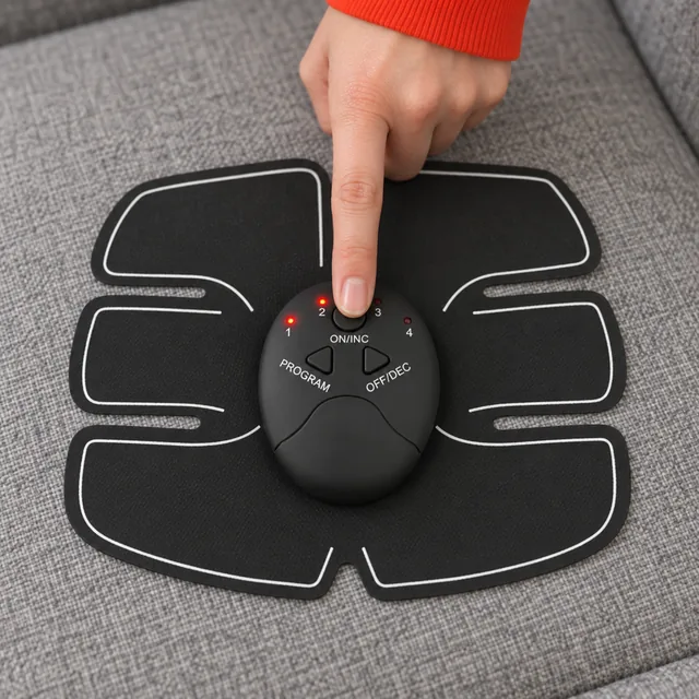 Eine Fingerspitze auf der Taste ON/INC der ovalen Steuereinheit in der Mitte des schwarzen Stymex-Pads, zwei rote LEDs leuchten