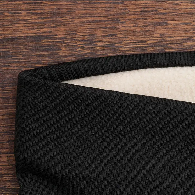 La cinturilla negra de las mallas WinterWeave, de cerca, sobre una mesa de madera oscura, con el forro polar color crema por dentro y la textura del tejido exterior a la vista